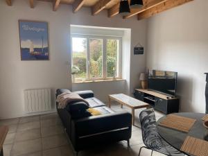 a living room with a couch and a tv at Gîte à la ferme de la Corbinais in Saint-Cast-le-Guildo