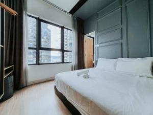 um quarto com uma grande cama branca e 2 janelas em Arte Plus Kuala Lumpur em Kuala Lumpur