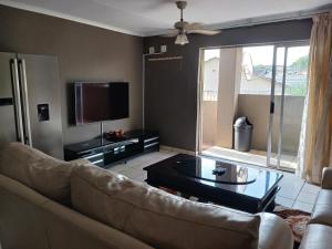 a living room with a couch and a tv at Tushiya guest lodge witbank in eMalahleni