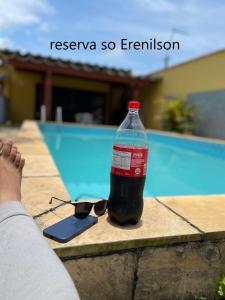 - une bouteille de coke et des lunettes de soleil à côté de la piscine dans l'établissement CASA TEMPORADA PRAIA GRANDE BAIXADA SANTISTA, à Solemar