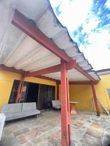 a patio with a roof with a bench and a table at CASA TEMPORADA PRAIA GRANDE BAIXADA SANTISTA in Solemar