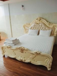 a white bed with an ornate frame in a bedroom at KHÁCH SẠN HOÀNG TRIỀU in Chánh Long