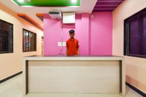 Jogeshwāri的住宿－OYO Hotel Raigad Inn，站在柜台后面的粉红色墙壁里的人