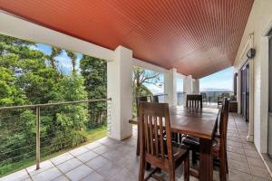 a dining room with a table and chairs on a balcony at Valley View House, Kangaroo Valley in Beaumont