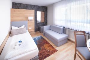 a small room with a bed and a chair and a couch at "Wendezeller Stuben" Weymann Gastronomiebetriebs GmbH in Wendeburg