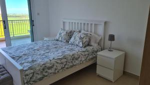 a bedroom with a bed with a night stand and a window at The Olive Grove Escape, Eleonas Apts in Sotira