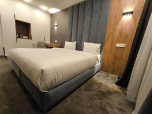 a bedroom with a large bed and a wooden wall at London Hotel Yerevan in Yerevan