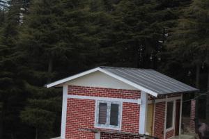 a small red and white house with a solar roof at The Deodar Stays in Kanatal