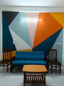 een woonkamer met een blauwe bank en 2 stoelen bij Happy HomeStay In Pondicherry in Pondicherry