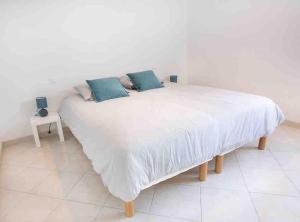 ein weißes Bett mit zwei blauen Kissen darauf in der Unterkunft La Grande Croisée extérieur et plage in Châtelaillon-Plage