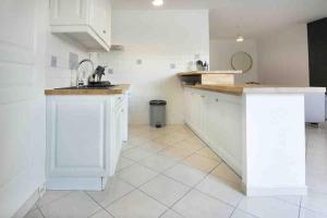 eine Küche mit weißen Schränken und einem Fliesenboden in der Unterkunft La Grande Croisée extérieur et plage in Châtelaillon-Plage