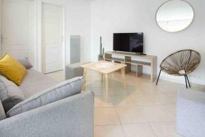 ein Wohnzimmer mit einer Couch, einem Tisch und einem Fernseher in der Unterkunft La Grande Croisée extérieur et plage in Châtelaillon-Plage