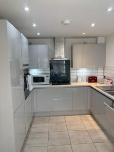 uma cozinha branca com armários e electrodomésticos brancos em The Chestnuts em Winscombe
