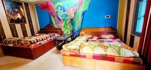 two beds in a room with a painting on the wall at Destination Of Choj ( DOC) in Kasol
