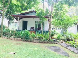 a white house with a porch and trees at Adventure Base camp in Kitulgala