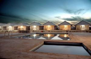 um hotel com piscina em frente a um grupo de tendas em Jaisalmer best desert Safari Camp em Jaisalmer