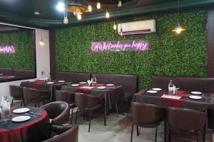 un restaurante con mesas y sillas y una pared verde en Tipsyy inn 017, en Gurgaon