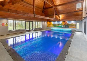 a swimming pool in a house with a wooden ceiling at Wagtail Cottage in Tosside