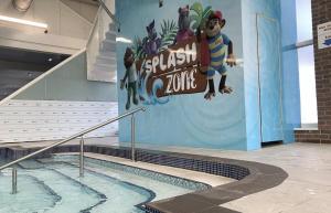 a swimming pool with a sign on the side of a building at Cozy Private Static Caravan at Llyons Robin Hood - Silver Birch Way 11 in Rhyl
