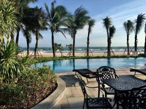 een zwembad met tafels en palmbomen en een strand bij Wonderland Villa at Hồ Tràm Beach in Xuyên Mộc