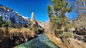 a river in a city with trees and buildings at Gaiamoment,com - Cueva las reinas in Alcalá del Júcar