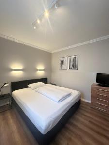 a bedroom with a large white bed and a television at Hotel Villa Solln in Munich