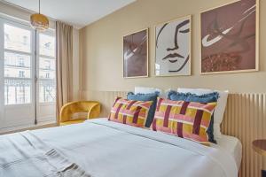 a bedroom with a large white bed with colorful pillows at Apartment Le Marais by Studio prestige in Paris