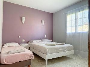 2 camas en un dormitorio con paredes de color púrpura y ventana en Villa de charme avec piscine, en Aguessac