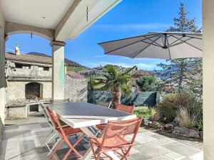 eine Terrasse mit einem Tisch, Stühlen und einem Sonnenschirm in der Unterkunft Villa de charme avec piscine in Aguessac