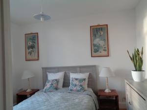 - une chambre avec un lit avec deux tables et deux photos sur le mur dans l'établissement vacances 34, au Crotoy