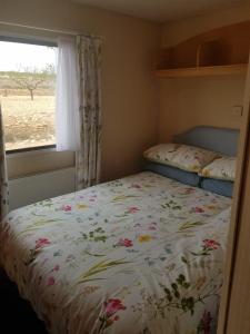 1 dormitorio con 1 cama con edredón de flores y ventana en Pinoso Mountain View Mobile Home Alicante Med Syndicate 4, en Murcia