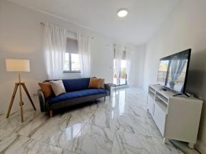 uma sala de estar com um sofá azul e uma televisão de ecrã plano em Penthouse with Large Terrace close to Seafront em St. Paul's Bay