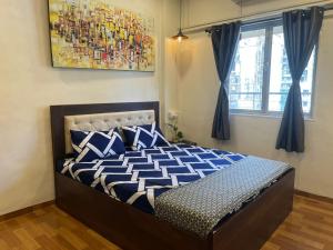 een slaapkamer met een bed met blauwe en witte kussens bij Sixth Sense Lokhandwala in Mumbai