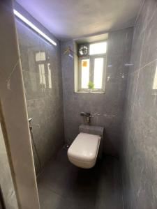 een kleine badkamer met een toilet en een raam bij Sixth Sense Lokhandwala in Mumbai