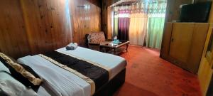 a bedroom with a bed and a chair and a television at Hotel New Broadway in Patnitop