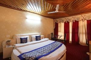 a bedroom with a large bed with a ceiling at Hotel New Broadway in Patnitop