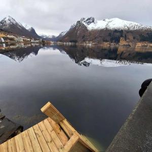 a chair sitting on the edge of a lake with snow covered mountains at Troll Fjordhytter in Syvde