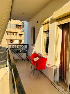 een balkon met rode stoelen en een tafel in een gebouw bij ALBI’S Apartment in Tirana