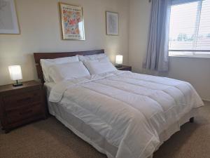 une chambre avec un grand lit blanc avec deux tables de nuit dans l'établissement Castro Place in Downtown San Leandro, à San Leandro