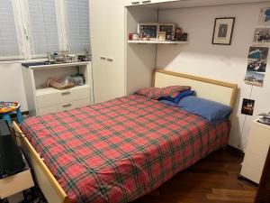 Un dormitorio con una cama con una manta a cuadros. en Villetta centro Imola 4 persone in matrimoniale, una piazza e mezzo e un singolo con parcheggio privato gratuito, en Imola