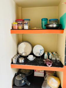 a shelf filled with pans and other kitchen items at Serene Homestay in Sibsāgar