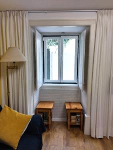 ein Wohnzimmer mit einem Fenster und 2 Tischen in der Unterkunft Lisbon Lovers in Lissabon