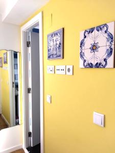 ein Zimmer mit einer gelben Wand mit Bildern darauf in der Unterkunft Lisbon Lovers in Lissabon