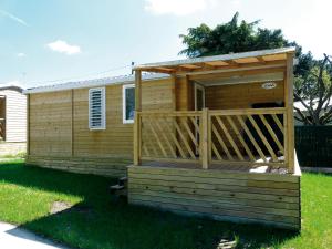 a wooden cabin with a deck in the grass at Camping Onlycamp du Moulin in Clisson