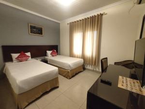 a hotel room with two beds and a desk at Hotel Cepu Indah 1 in Cepu