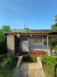 ein kleines Haus mit einer Veranda und einer Tür in der Unterkunft PALM Springs Bed & Breakfast in Limbe