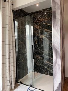 een glazen douche in een kamer met een gordijn bij La Maison Bateau au Bord de Mer in Guissény