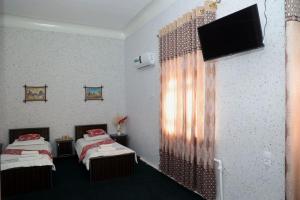 a room with two beds and a flat screen tv at World Guest House in Samarkand