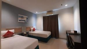 a hotel room with two beds and a window at Hotel Cepu Indah 2 in Cepu
