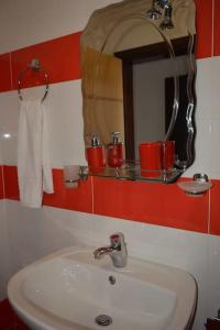 ein Bad mit einem Waschbecken, einem Spiegel und roten Wänden in der Unterkunft Pogradec Sunilio Apartment in Pogradec